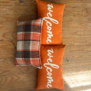 3 indoor/outdoor pillows. Welcome burnt orange with plaid backs.